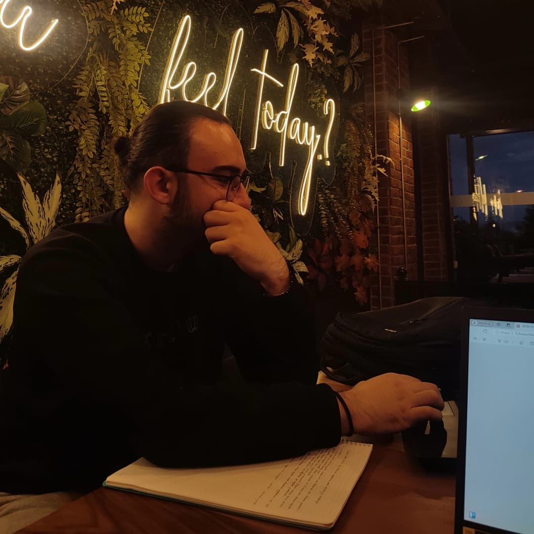 Furkan Söyleyici working on a laptop at a café in the evening